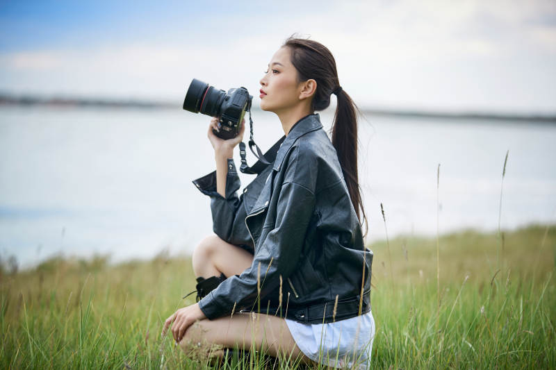 户外湖畔进行拍摄的亚洲青年女性摄影师图片