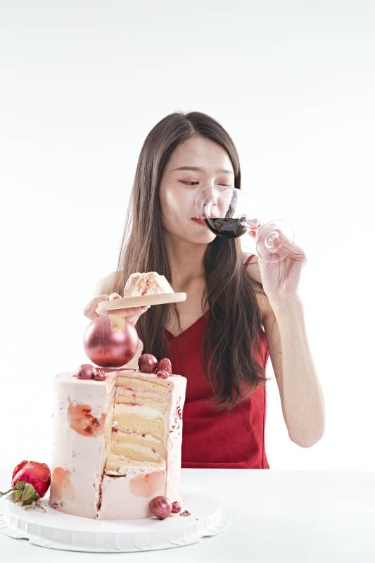 喝红酒品尝蛋糕的年轻女性图片
