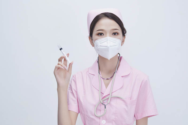 穿护士服戴听诊器口罩手执针筒的年轻女护士图片