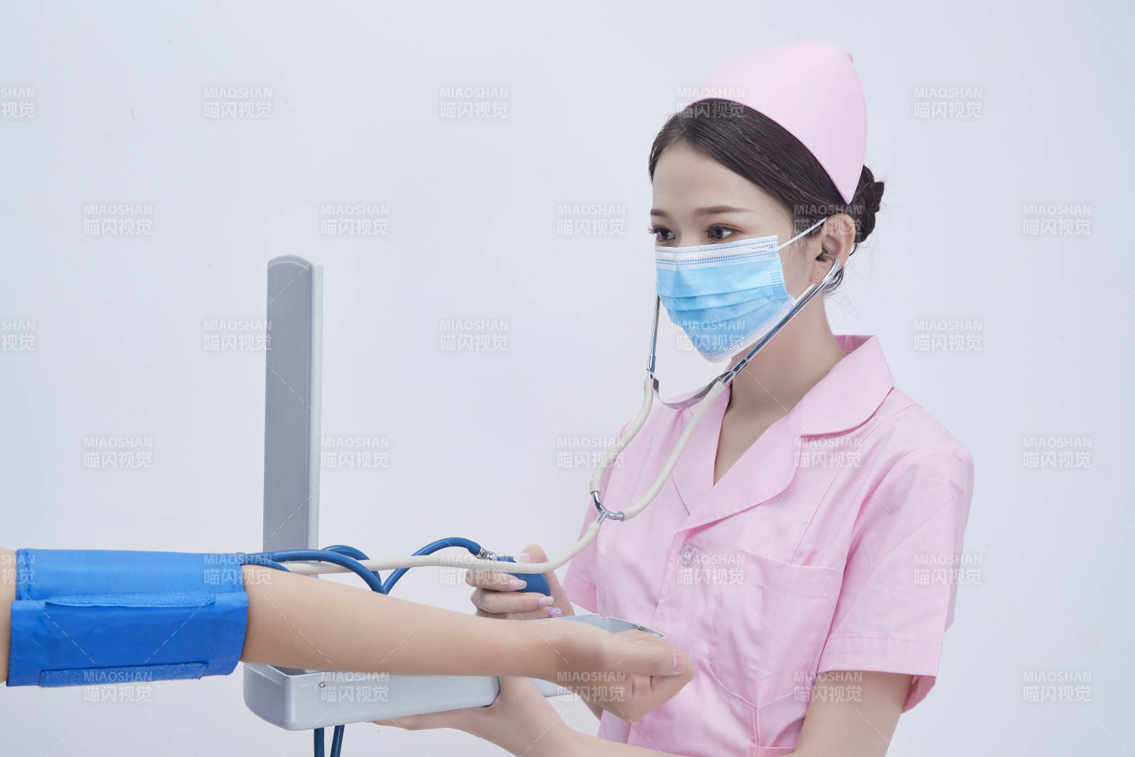 手拿血压测量仪为患者诊治量血压的女性护士图片