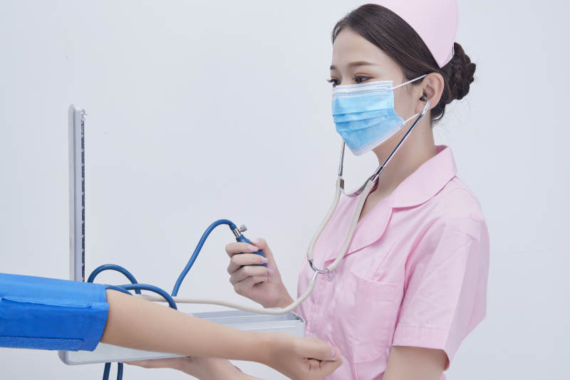 手拿血压测量仪为患者诊治量血压的女性护士图片