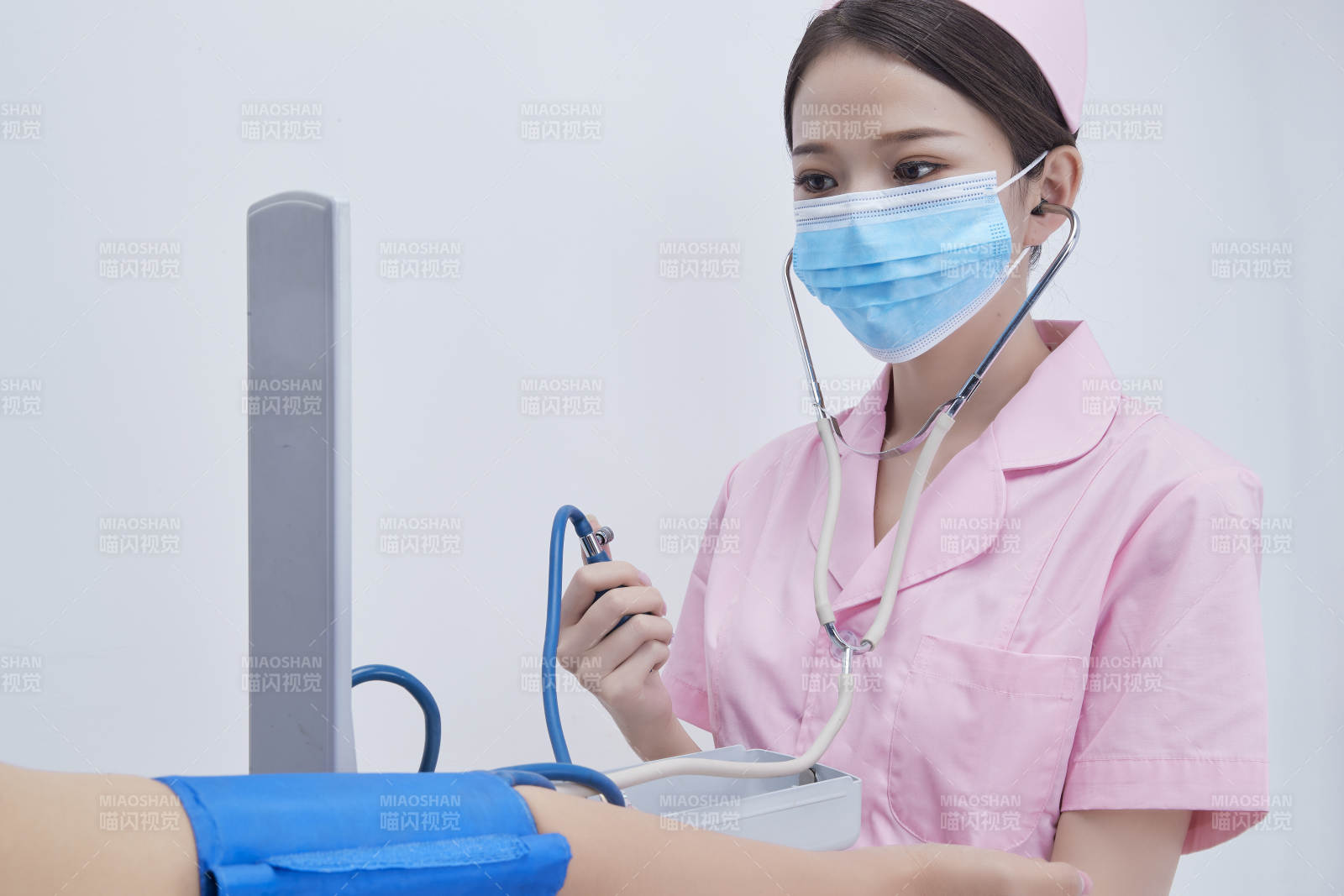 手拿血压测量仪为患者诊治量血压的女性护士图片