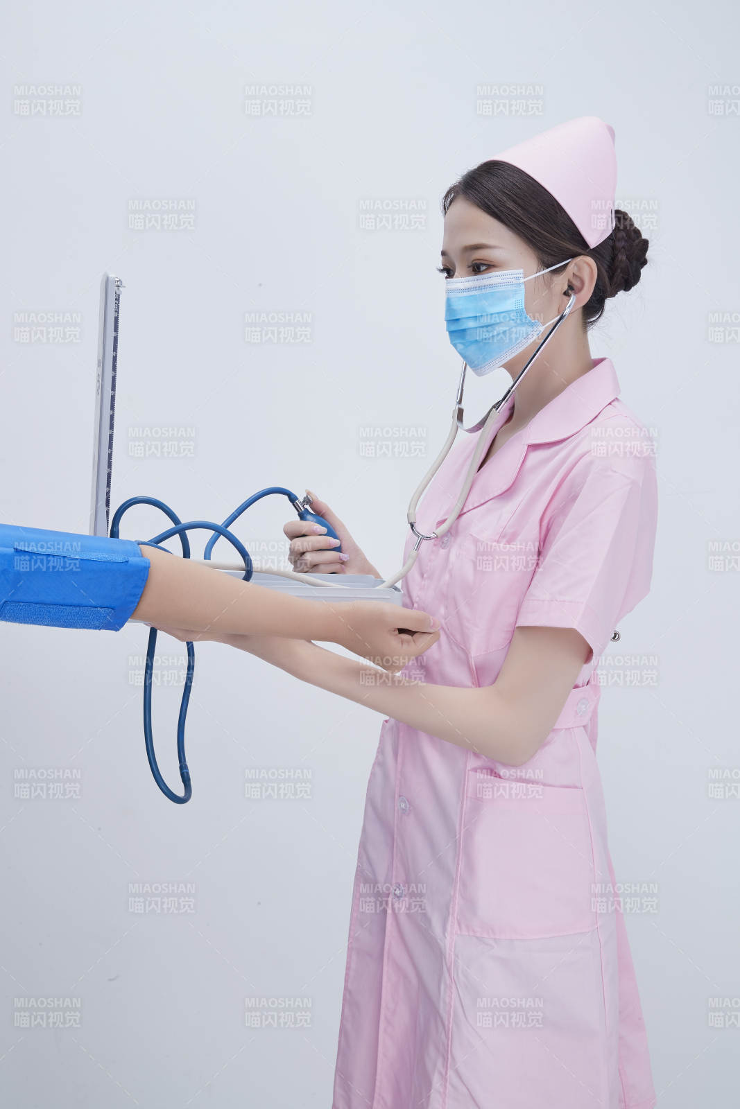 手拿血压测量仪为患者诊治量血压的女性护士图片