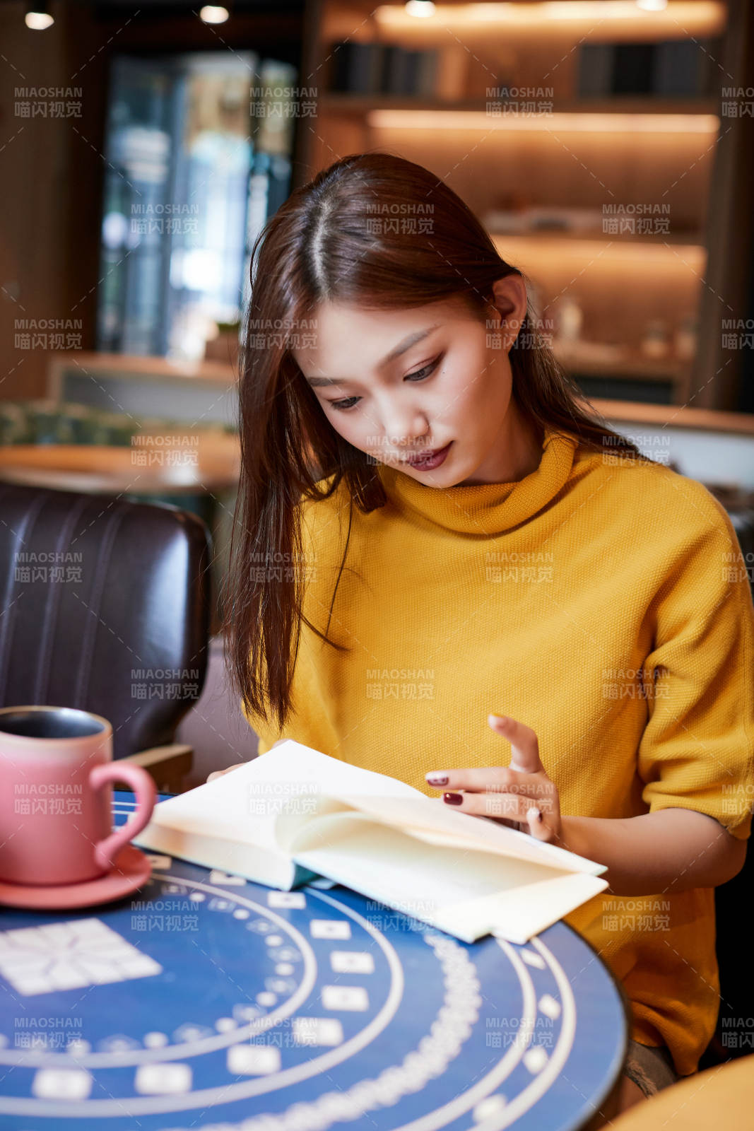 在图书咖啡馆阅读书籍的少女图片