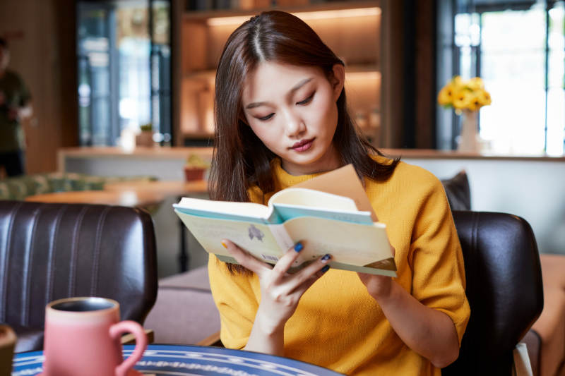 在图书咖啡馆阅读书籍的少女图片