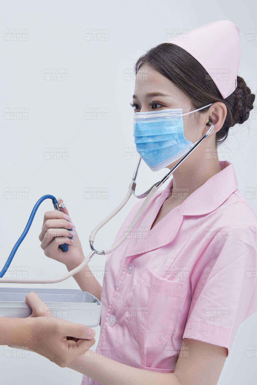 手拿血压测量仪为患者诊治量血压的女性护士图片