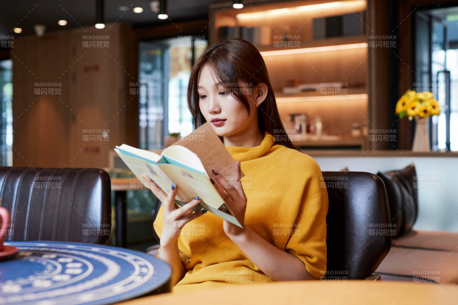 在图书咖啡馆阅读书籍的少女图片