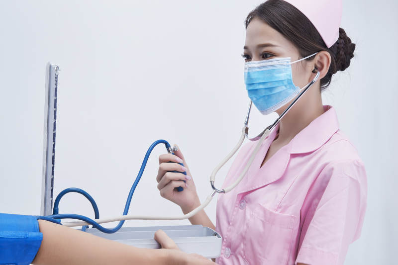 手拿血压测量仪为患者诊治量血压的女性护士图片