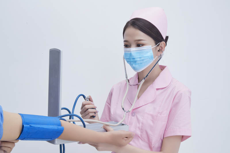 手拿血压测量仪为患者诊治量血压的女性护士图片