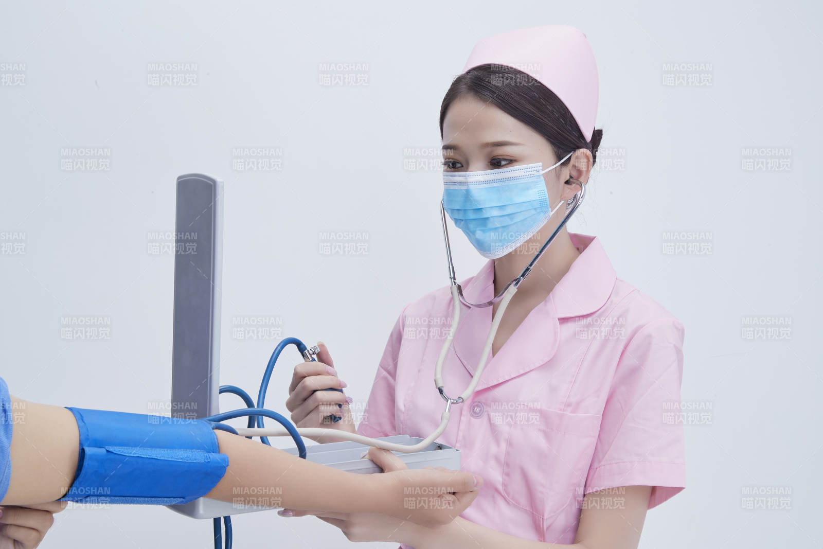 手拿血压测量仪为患者诊治量血压的女性护士图片