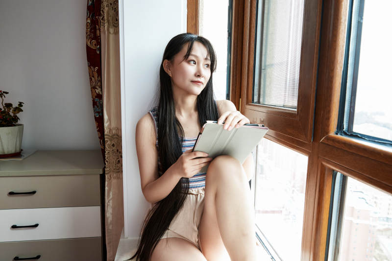 躺在舒适的飘窗上听音乐追剧的亚洲少女图片