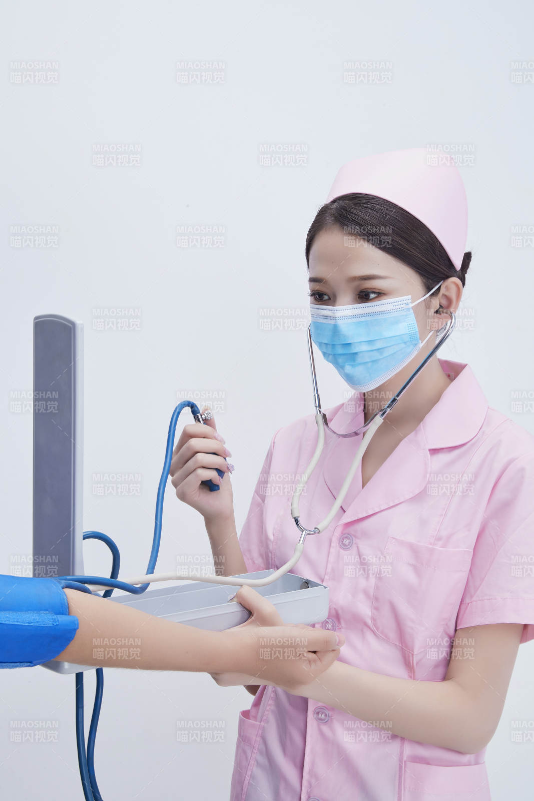 手拿血压测量仪为患者诊治量血压的女性护士图片