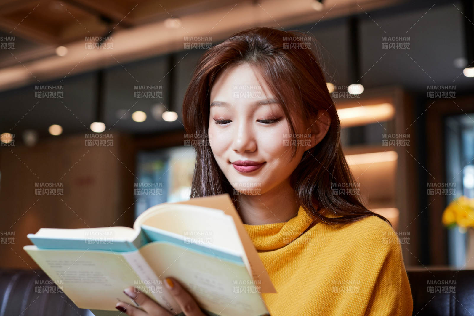 在图书咖啡馆阅读书籍的少女图片