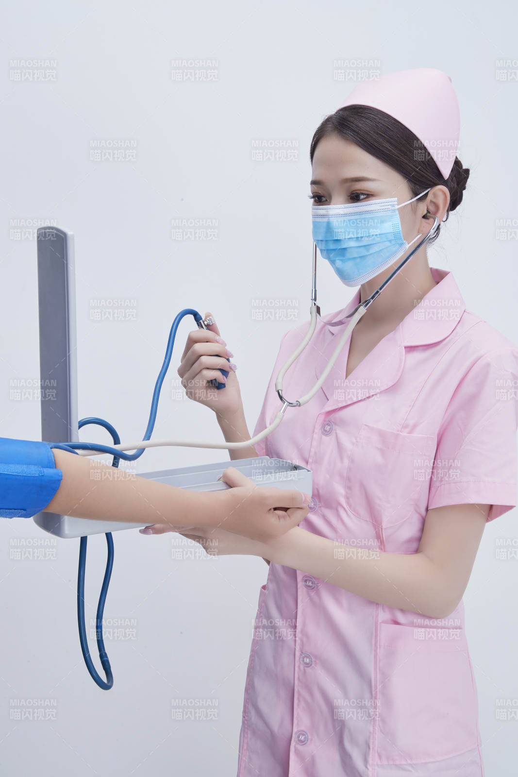 手拿血压测量仪为患者诊治量血压的女性护士图片