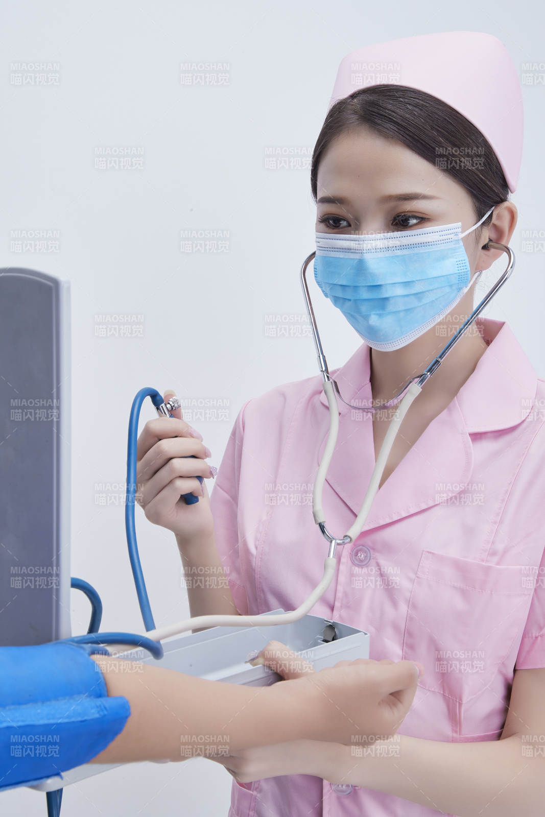 手拿血压测量仪为患者诊治量血压的女性护士图片