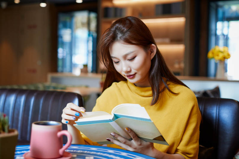 在图书咖啡馆阅读书籍的少女图片