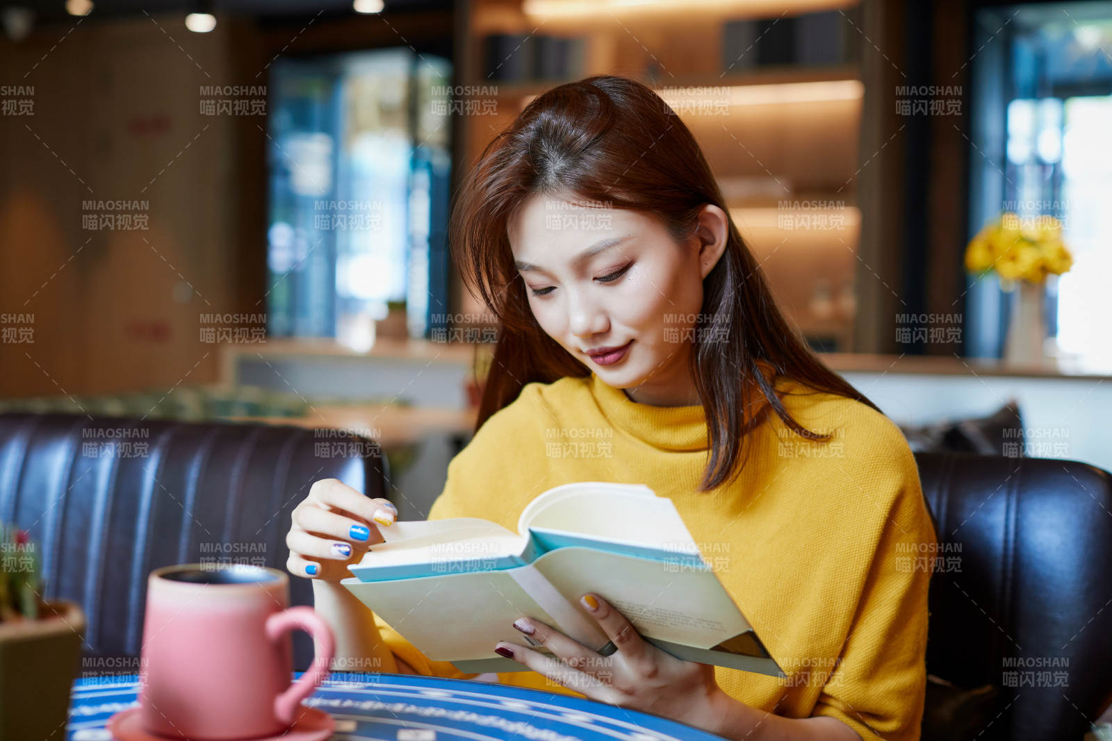 在图书咖啡馆阅读书籍的少女图片