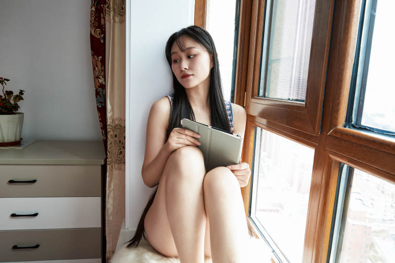 躺在舒适的飘窗上听音乐追剧的亚洲少女图片