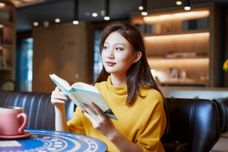 在图书咖啡馆阅读书籍的少女图片