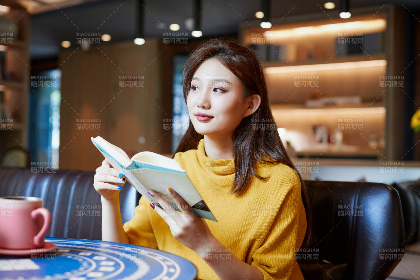 在图书咖啡馆阅读书籍的少女图片