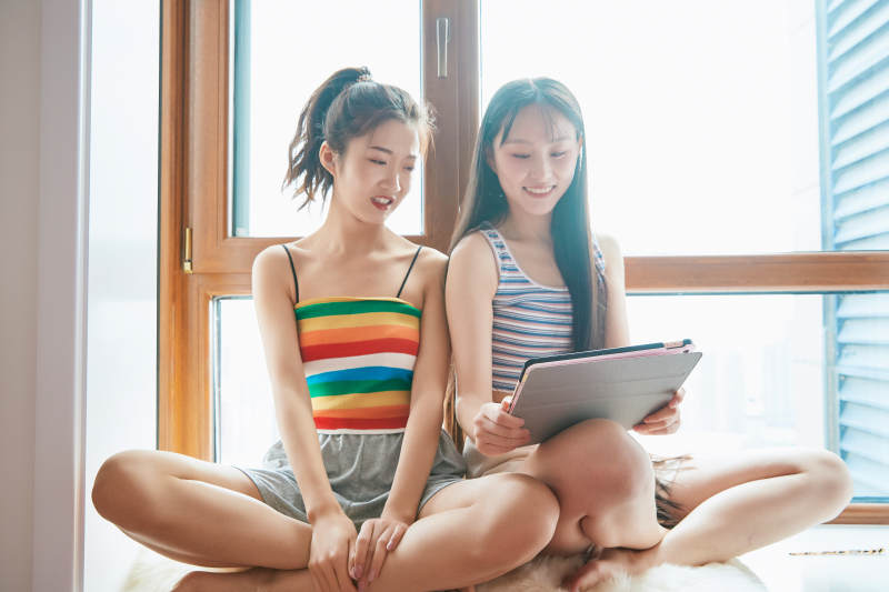 午后坐在飘窗上追剧休息的闺蜜少女图片