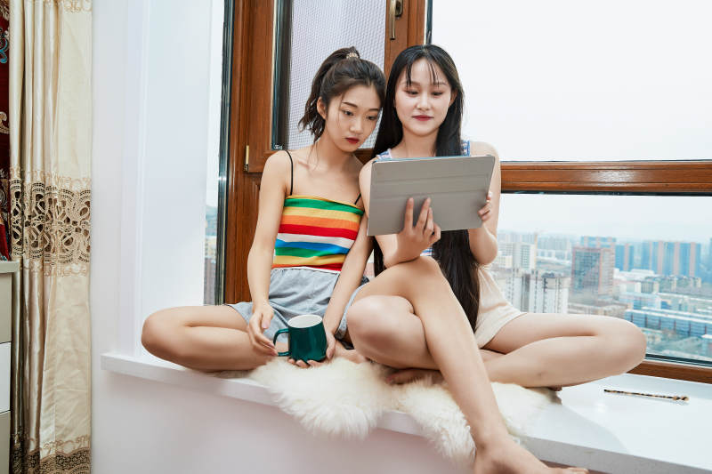 午后坐在飘窗上追剧休息的闺蜜少女图片