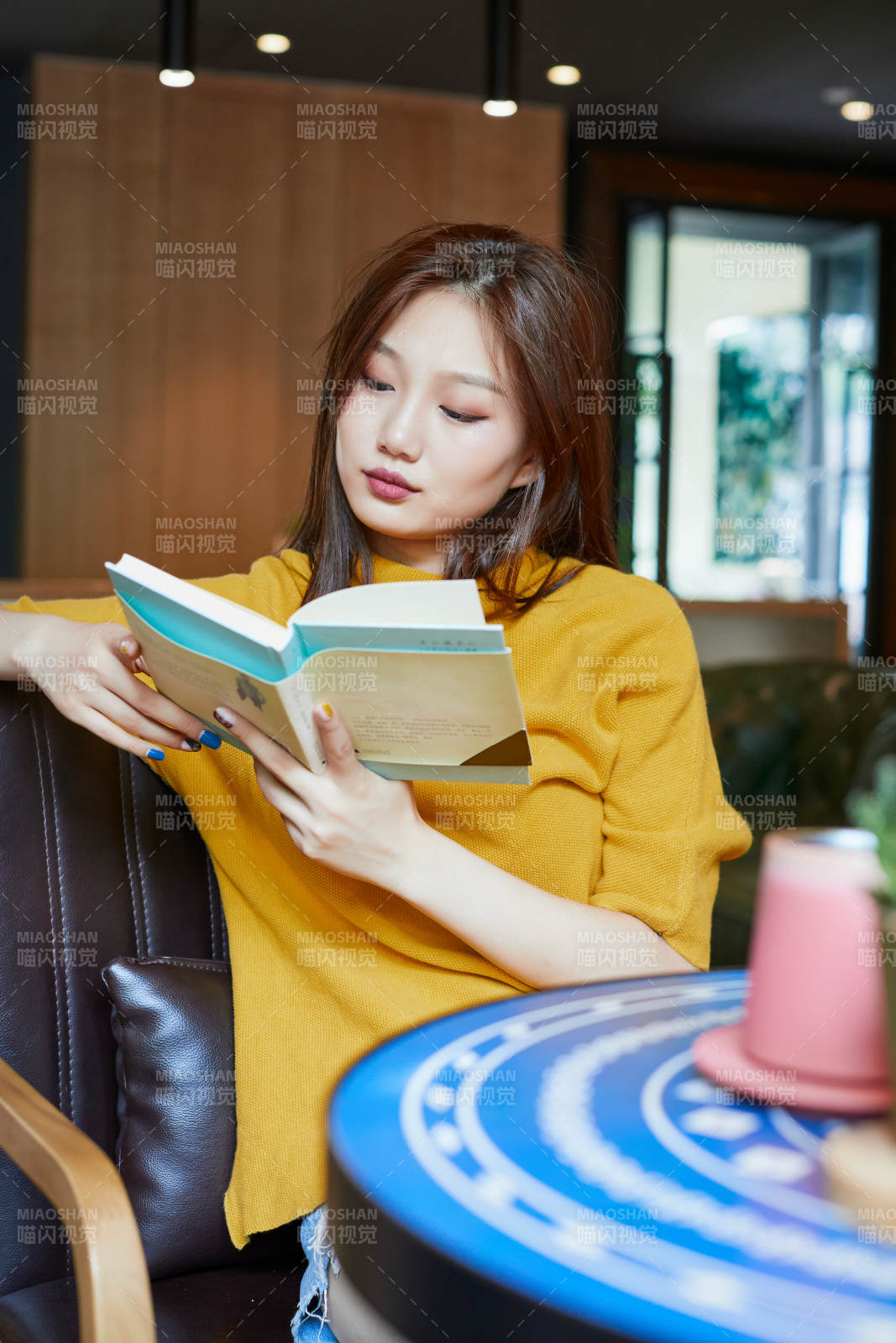 在图书咖啡馆阅读书籍的少女图片