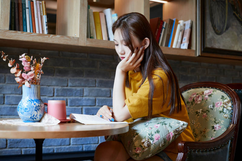 在图书咖啡馆阅读书籍的少女图片
