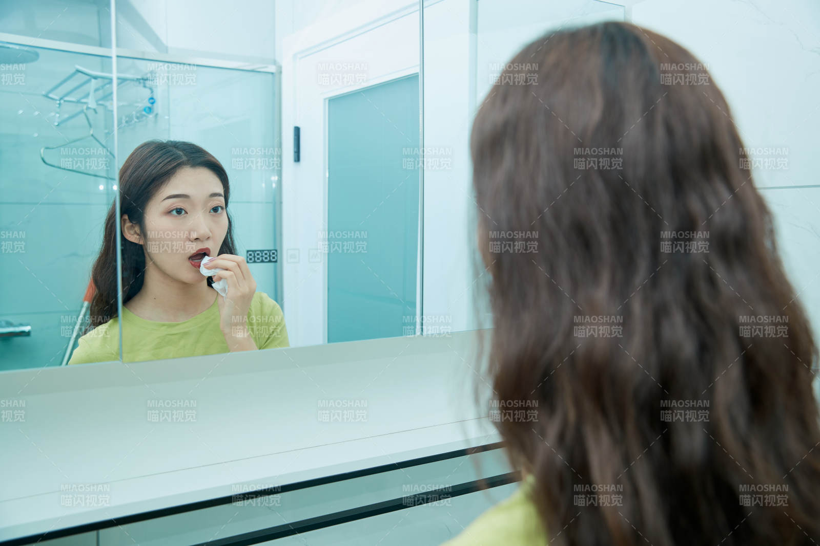 在卫生间对着镜子整理妆容的亚洲少女图片