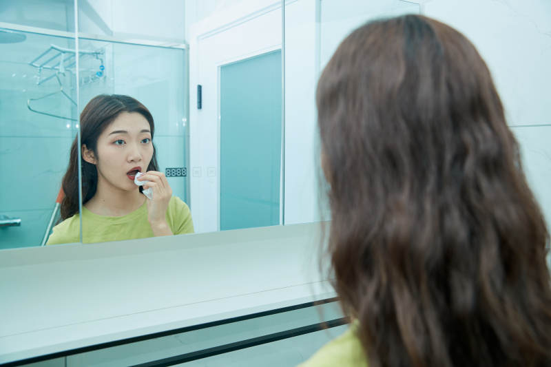 在卫生间对着镜子整理妆容的亚洲少女图片