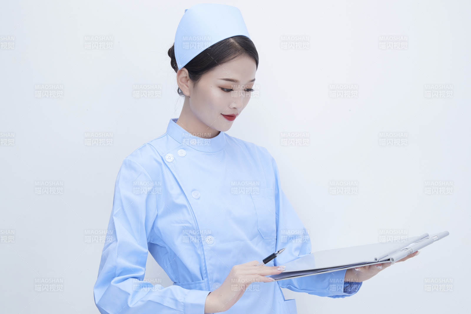 白背景里穿蓝色护士服手持病历夹的美女护士图片