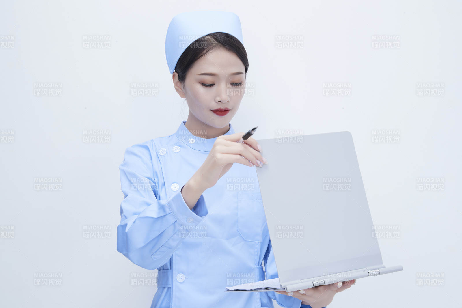 白背景里穿蓝色护士服手持病历夹的美女护士图片