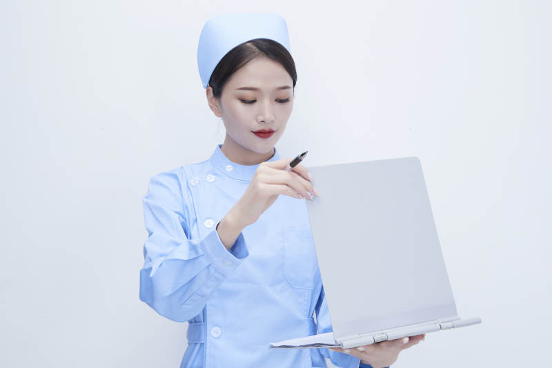 白背景里穿蓝色护士服手持病历夹的美女护士图片