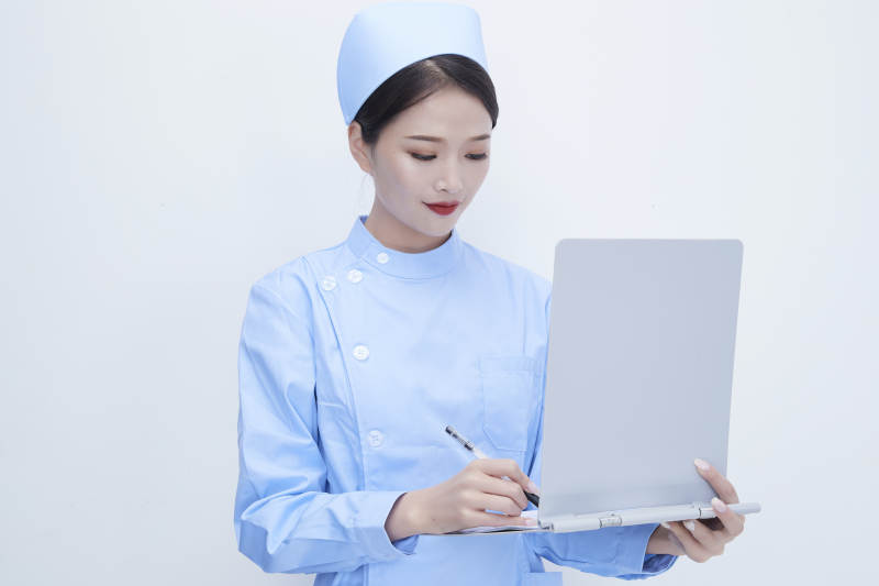 白背景里穿蓝色护士服手持病历夹的美女护士图片