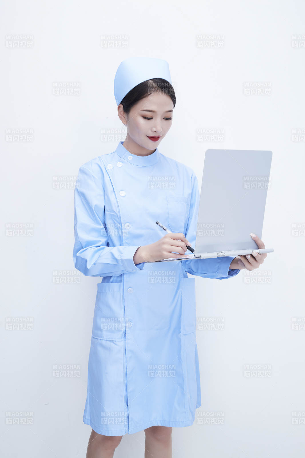 白背景里穿蓝色护士服手持病历夹的美女护士图片