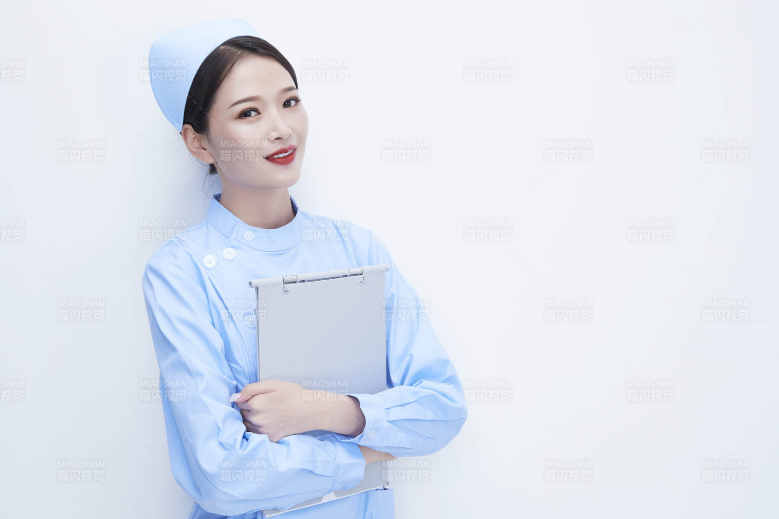 白背景里穿蓝色护士服手持病历夹的美女护士图片