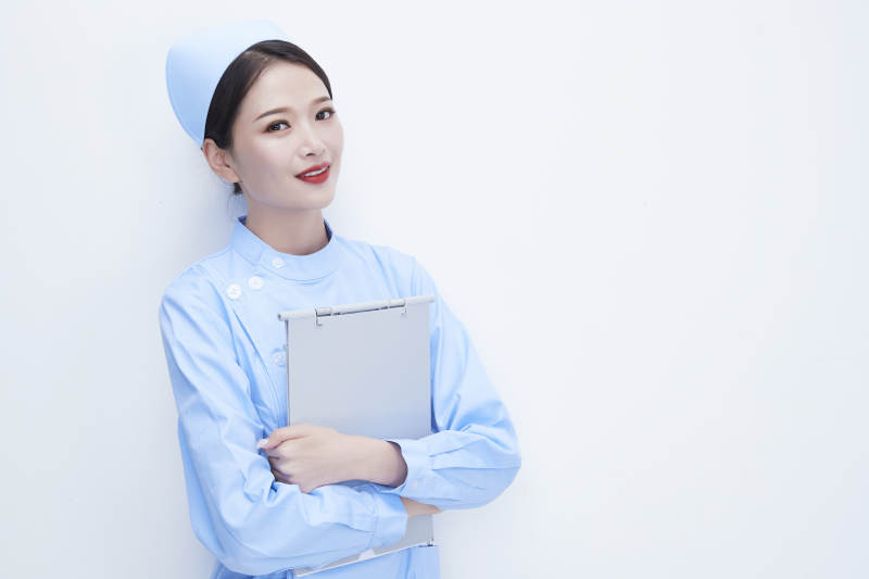 白背景里穿蓝色护士服手持病历夹的美女护士图片