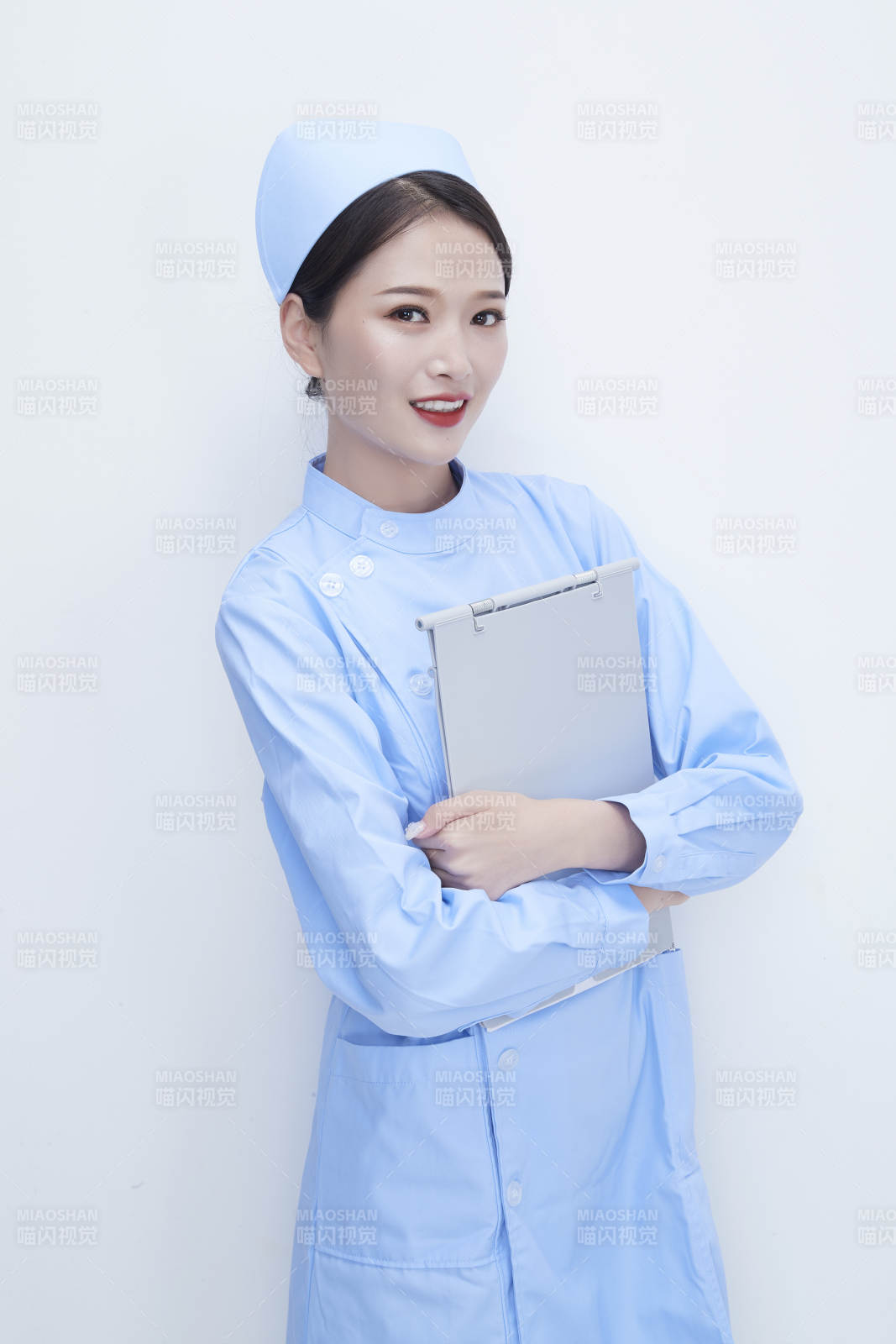 白背景里穿蓝色护士服手持病历夹的美女护士图片