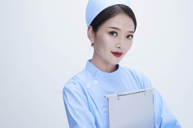 白背景里穿蓝色护士服手持病历夹的美女护士图片