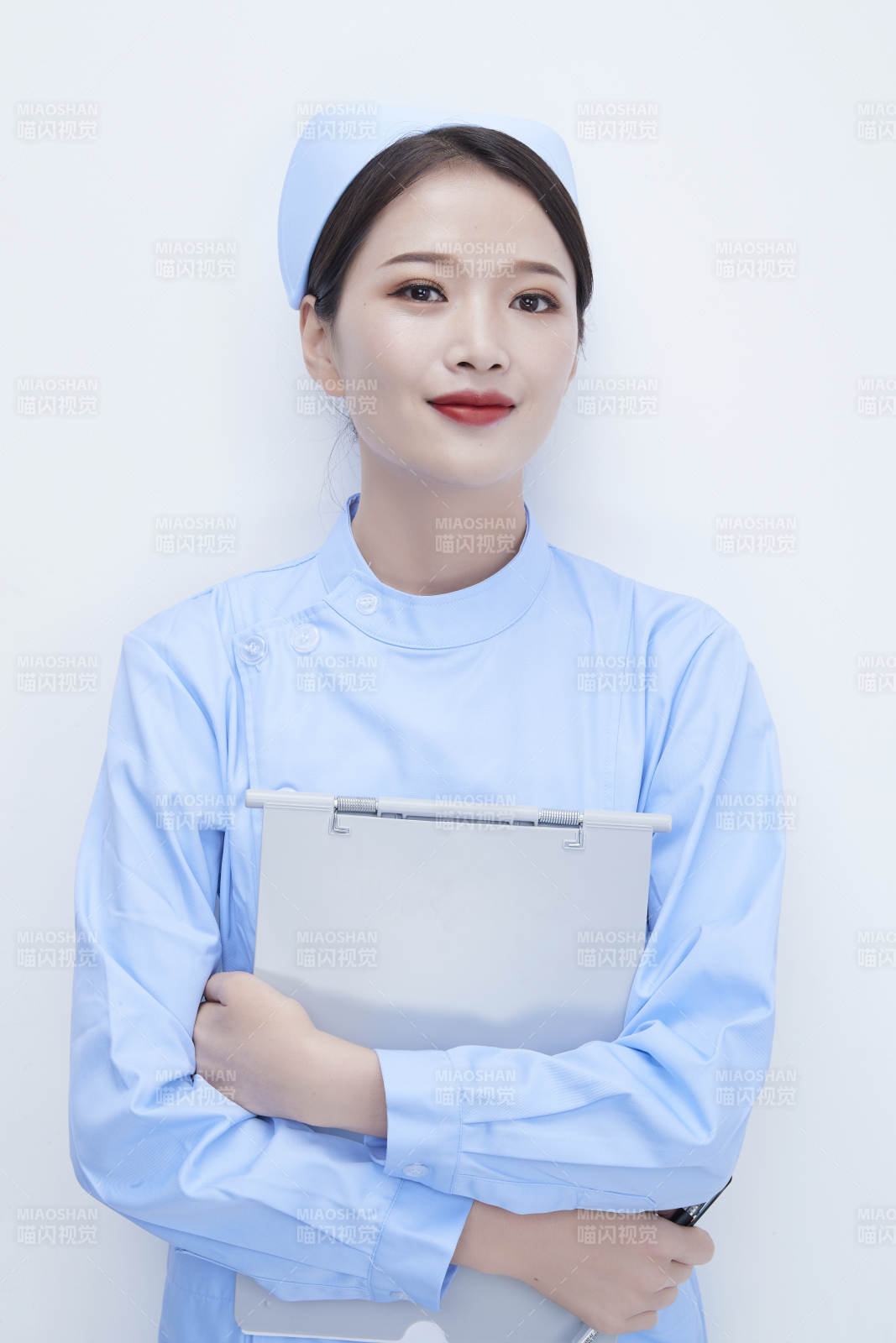 白背景里穿蓝色护士服手持病历夹的美女护士图片