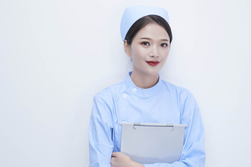 白背景里穿蓝色护士服手持病历夹的美女护士图片