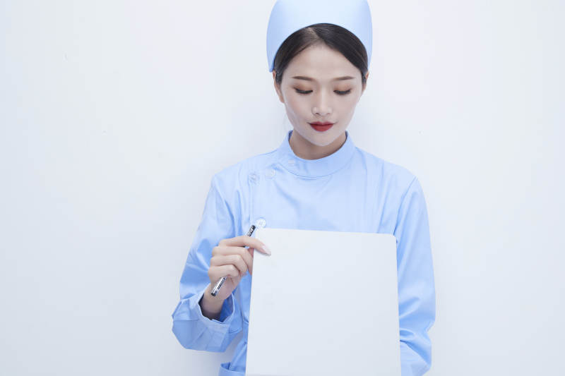 白背景里穿蓝色护士服手持病历夹的美女护士图片