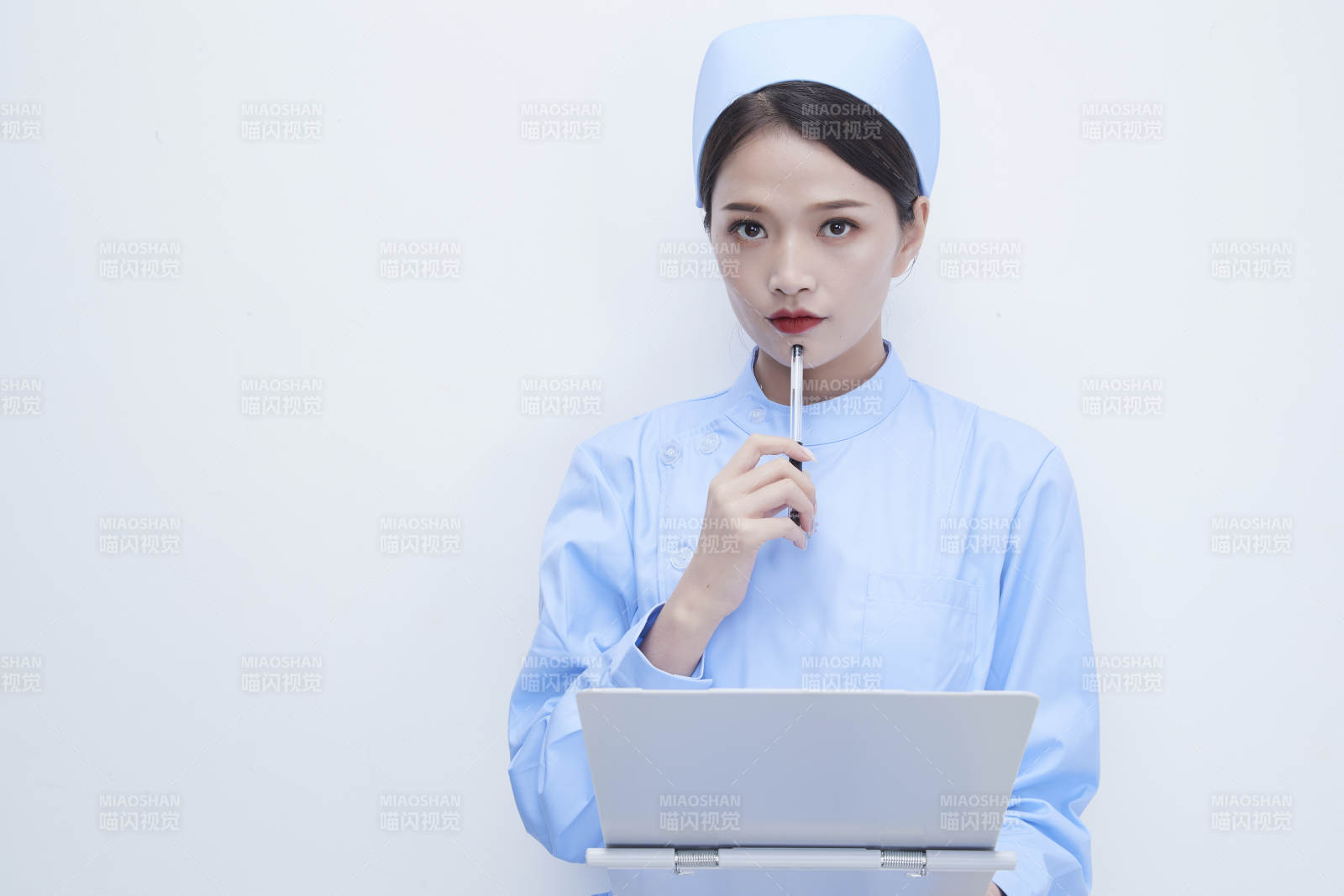 白背景里穿蓝色护士服手持病历夹的美女护士图片