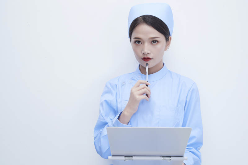白背景里穿蓝色护士服手持病历夹的美女护士图片