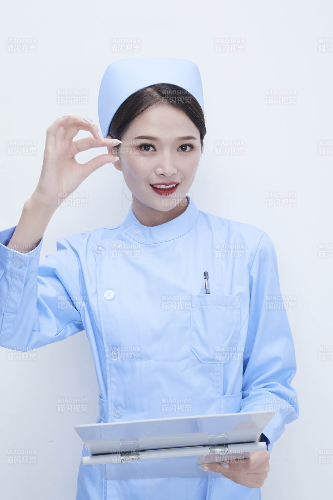 白背景里穿蓝色护士服手持病历夹的美女护士图片