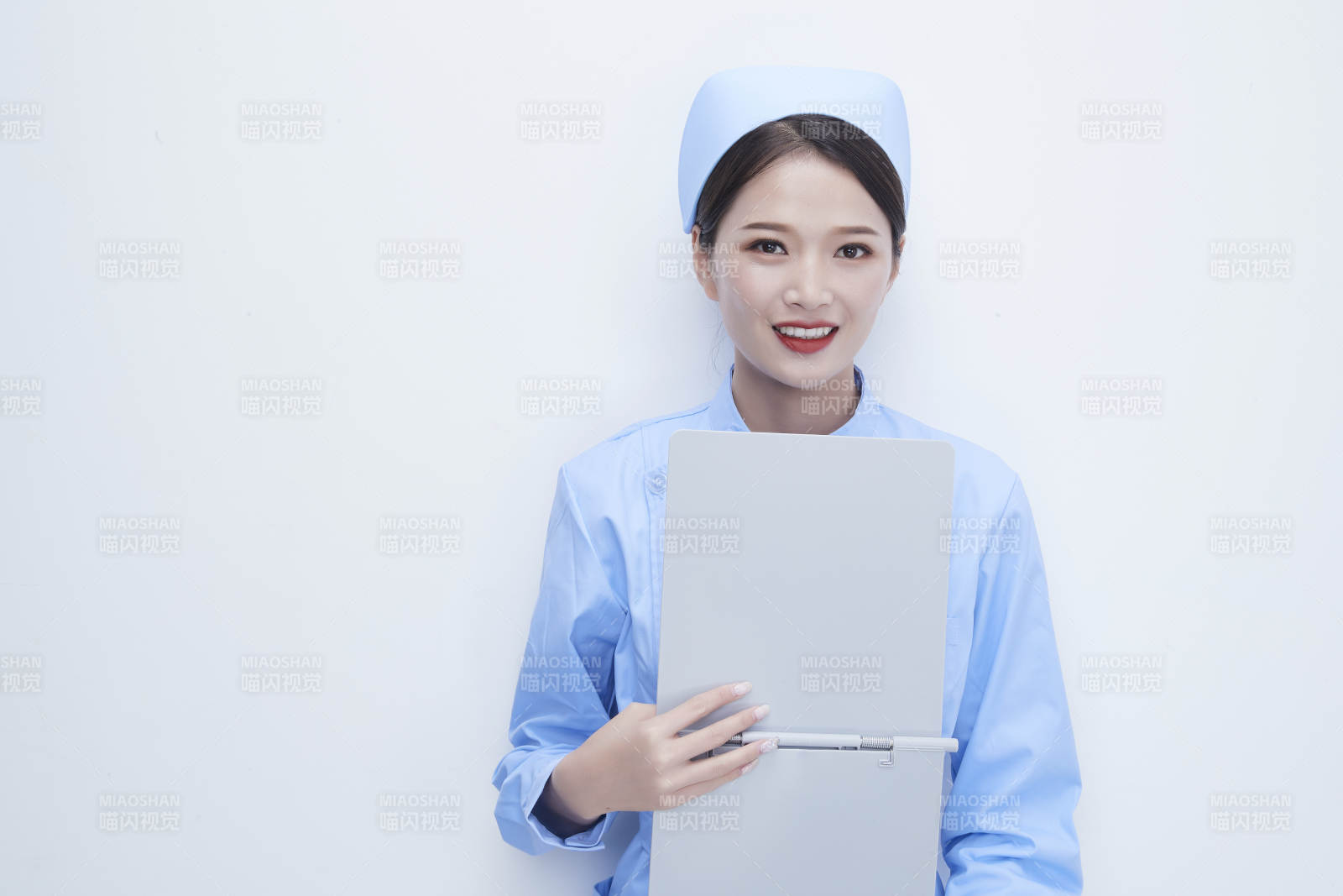 白背景里穿蓝色护士服手持病历夹的美女护士图片