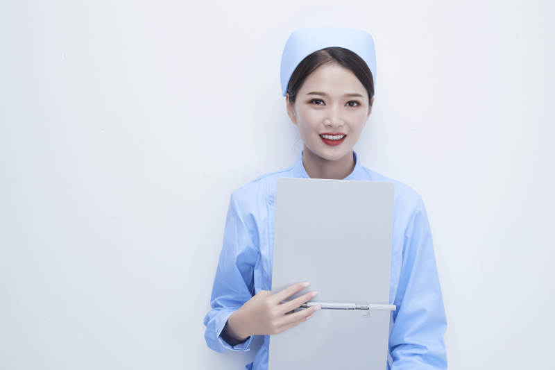 白背景里穿蓝色护士服手持病历夹的美女护士图片