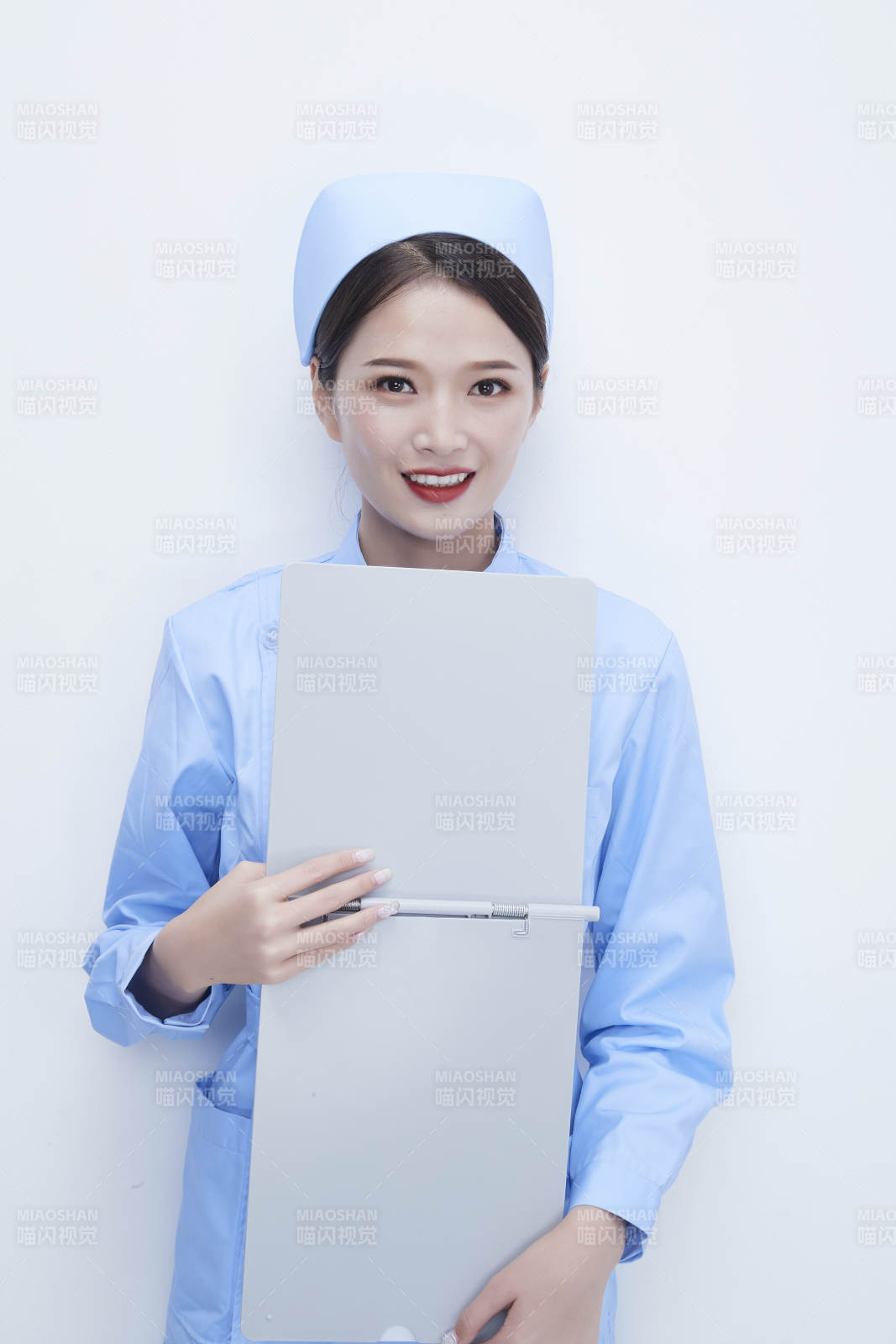白背景里穿蓝色护士服手持病历夹的美女护士图片