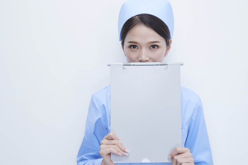 白背景里穿蓝色护士服手持病历夹的美女护士图片
