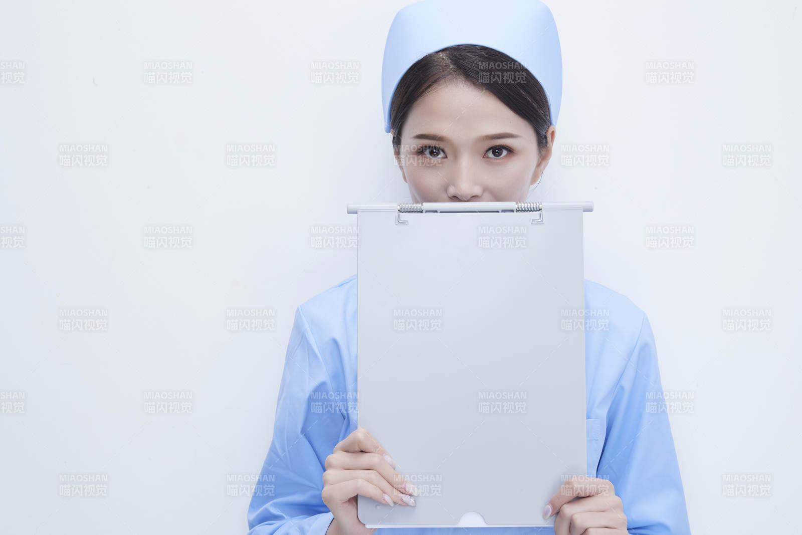 白背景里穿蓝色护士服手持病历夹的美女护士图片